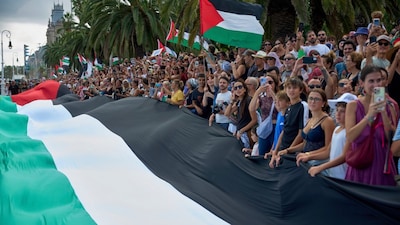 People hold Palestinian flags as they bid farewell to activists setting sail on their boats to join a civilian flotilla bound for Gaza. (AP file photo)