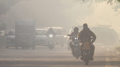 Commuters make their way amid low visibility on a hazy morning. (PTI photo)
