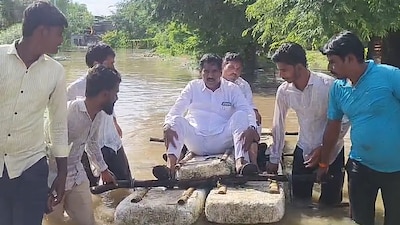 A viral photo from Majalgaon shows locals wading through floodwaters to drag a boat carrying NCP (Sharad Pawar) MP Bajrang Sonawane, who remained seated as he toured the inundated area. (IMAGE: SOURCED)