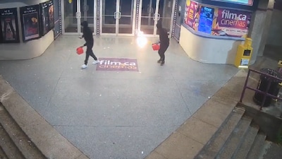 In the security camera footage provided by the Halton Police Department, the arsonists are seen tossing a flame after spraying the entrance of a cinema hall in Toronto with a flammable liquid. (IMAGE: HALTON POLICE DEPARTMENT/SOURCED)