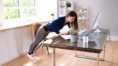 Place your hands on the edge of your desk and perform push-ups at a 45-degree angle.Why it works: It strengthens your chest, shoulders, and triceps without needing gym equipment. Plus, it helps improve posture by working against the hunching caused by long computer hours.