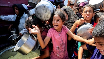Palestinians wait to receive food from a charity kitchen, in Khan Younis, southern Gaza Strip. (IMAGE: REUTERS) 