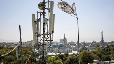 A Taliban flag flutters near telecom equipment installed over a rooftop providing internet services as the Taliban administration banned fibre-optic internet in Balkh province. (Image: Atif ARYAN/AFP)