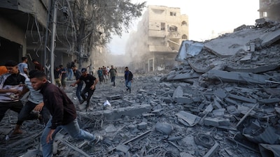 People run for cover following an Israeli strike that targeted a building in the Bureij camp for Palestinian refugees in the central Gaza Strip on October 19. (AFP photo)
