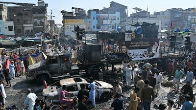 Locals look at the remains of charred vehicles following violent clashes between police personnel and anti-Israel protesters from the TLP party in Muridke. (AFP photo)
