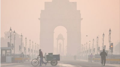 New Delhi: The India Gate shrouded in a layer of smog as people make their way during a cold winter morning (Photo: PTI)