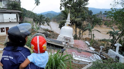 A woman holding a child looks at a damaged temple following a landslide in the aftermath of Cyclone Ditwah in Gampola in Kandy district, Sri Lanka. (IMAGE: REUTERS) 