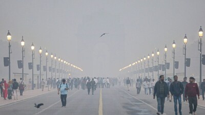 Smog engulfs Kartavya Path as people take a stroll amid low visibility, near the India Gate in New Delhi on December 13, 2025. (Image: PTI)