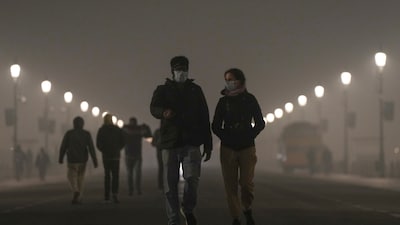 Pedestrians wear masks as a layer of smog engulfs the city amid deterioration in the capital's air quality, in New Delhi, Thursday, Dec. 18, 2025. (Image: PTI)