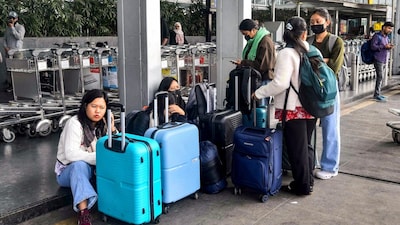 Passengers wait with their luggage outside the Netaji Subhas Chandra Bose International Airport amid IndiGo Flight Cancellations in Kolkata. (PTI photo)
