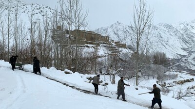 Afghan men spread dirt on a snow-covered path following the snowfall in the Dara district of Panjshir province on January 23, 2026. Snow and heavy rain have killed 61 people in Afghanistan, the disaster management authority said on January 24. (Photo by Shah Poor AFZALLY / AFP)