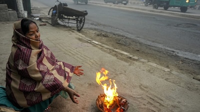A woman warms herself around a small fire on a foggy winter morning, in New Delhi. (IMAGE: PTI) 