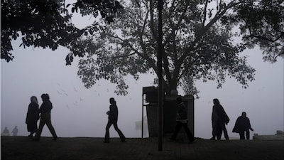 New Delhi: People stroll as a layer of dense fog shrouds the city on a cold winter morning (Photo: PTI)