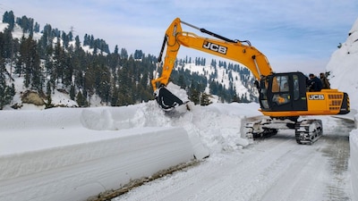 An excavator removes snow along the Mughal Road, that connects Shopian district with Poonch-Rajouri, after fresh snowfall, in Shopian district, Jammu and Kashmir. (PTI)