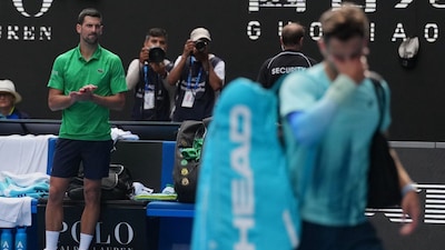 Novak Djokovic, left, of Serbia reacts as Lorenzo Musetti of Italy walks from the court after withdrawing from their quarterfinal match at the Australian Open tennis championship in Melbourne, Australia, Wednesday, Jan. 28, 2026. (AP Photo/Dita Alangkara)