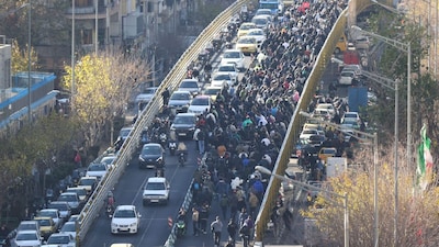 Shopkeepers and traders walk over a bridge during a protest against the economic conditions and Iran's embattled currency in Tehran on December 29, 2025. (AFP)