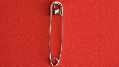 A safety pin’s hole and coil create a spring mechanism that secures the sharp tip, preventing accidental openings and injuries.