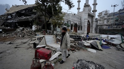 A man walks past scattered belongings after the demolition of alleged encroachments near the Syed Faiz Elahi mosque at Turkman Gate area of New Delhi on January 7, 2025. (PTI)