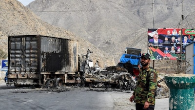 A security personnel stands guard near charred truck containers torched by armed separatist group Balochistan Liberation Army (BLA) at central Bolan district. (AFP photo)
