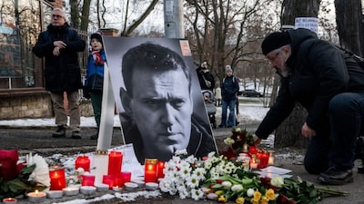 A mourner lays flowers at a makeshift memorial for late Russian opposition leader Alexei Navalny, marking the first anniversary of his death. (AFP/File)