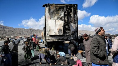 People gather as others collect recyclable items beside a burnt vehicle along a road on the outskirts of Quetta on February 1, 2026 a day after an attack by Baloch separatists. (Image: AFP)