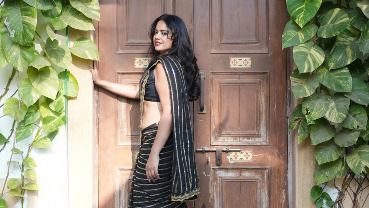 Sameera Reddy holding a designer bag and smiling