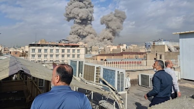 People watch as smoke rises on the skyline after an explosion in Tehran, Iran on February 28, 2026. (AP Photo)