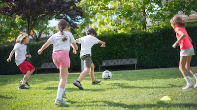 Physical activity, like playing football with kids their age, is important for growing children.