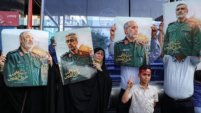 People hold up pictures of slain Islamic Revolutionary Guard Corps (IRGC) commanders as they attend a rally in solidarity with the government against Israel's attacks. (AFP)