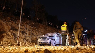 Israeli security forces inspect a damaged car after a missile struck a road in Jerusalem. (AFP)