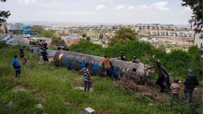 Children move a part of an Iranian missile remnant that fell in a school courtyard in the Israeli settlement of Peduel, in the occupied West Bank (Photo: AFP)