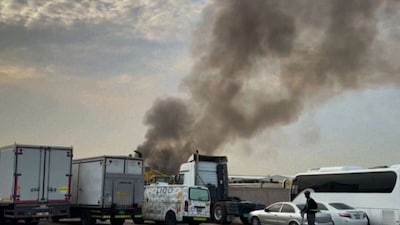 A man riding past as smoke rises from a fire which, according to the authorities was caused by a successful interception, at Dubai's Al Quoz Industrial area, United Arab Emirates, Friday, March 13, 2026. (AP Photo)
