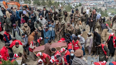 Afghanistan people and Taliban soldiers place coffins of victims killed in a Pakistani air strike on a drug rehabilitation centre, into a mass grave. (AFP)