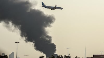 An international low coast FlyDubai aircraft prepares for landing as a smoke plume rises from an ongoing fire near Dubai International Airport in Dubai on March 16, 2026. (Photo: AFP)