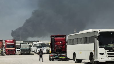 A man walks in a parking area as smoke rising from the port of Jebel Ali after a reported Iranian strike in Dubai on March 1. (AFP photo)