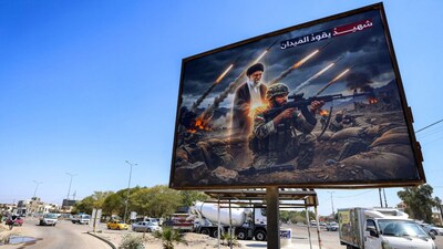 A billboard depicts Ayatollah Ali Khamenei, Iran’s late supreme leader, standing behind an Iranian soldier with a caption in Arabic reading “a martyr leads the battlefield”. (AFP)