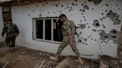 Kurdish fighters, members of The Organization of Iranian Kurdistan Struggle (Sazmani Khabat), walks past a damaged building after an Iranian drone attack to their base near Erbil, in Iraq's northern autonomous Kurdish region on March 9, 2026. (Photo: AFP)