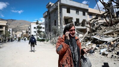  A woman talks on a phone while standing amid a damaged residential neighbourhood hit by a strike as the US-Israeli conflict with Iran continues, in Tehran, Iran. (IMAGE: REUTERS) 