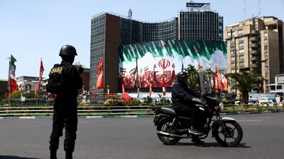 A member of a police force stands guard on a street, amid the US-Israeli conflict with Iran, in Tehran, Iran. (IMAGE: REUTERS) 