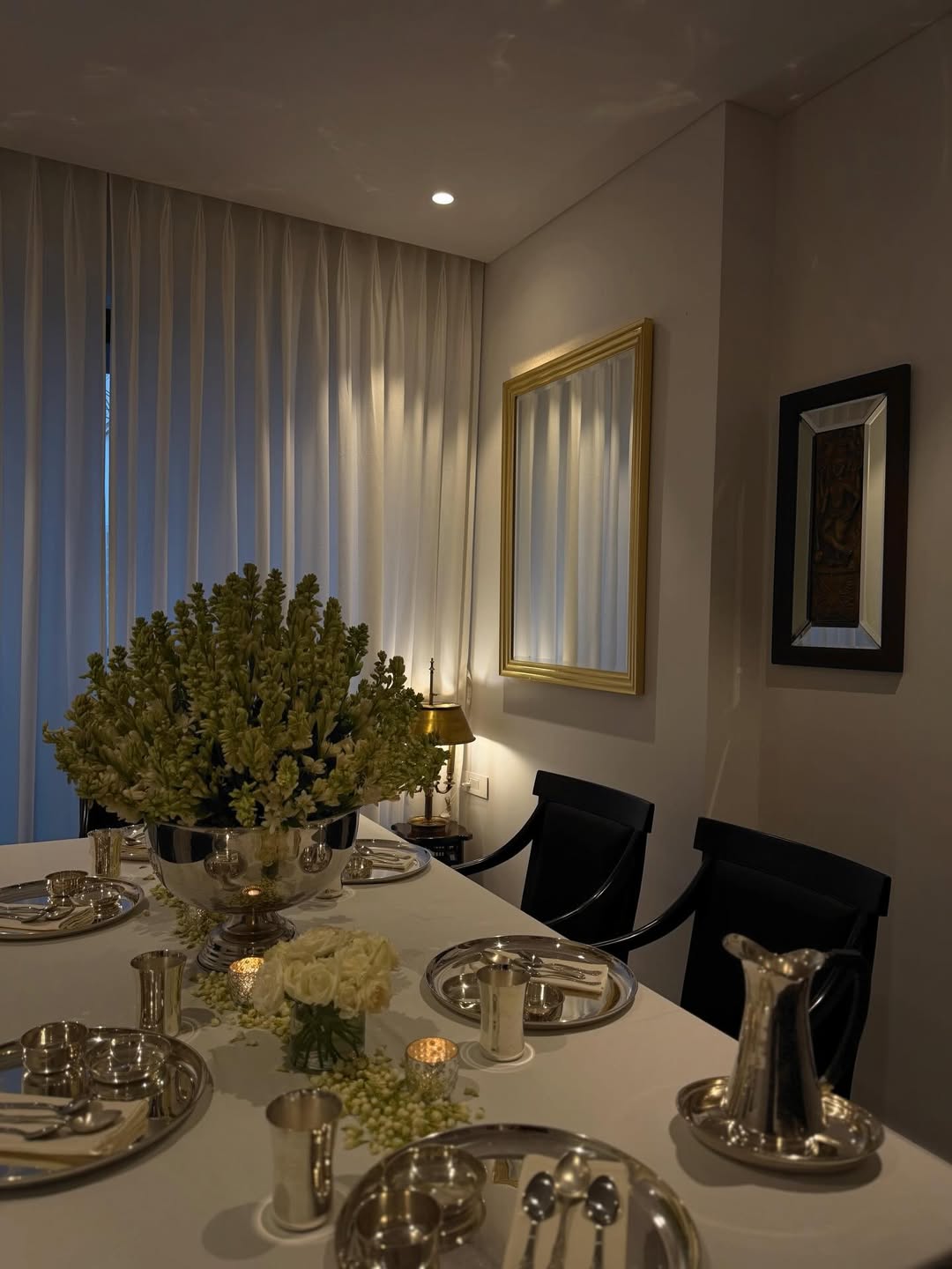 The dining area continues the home’s understated elegance with a simple yet carefully curated setup. A rectangular table is neatly arranged with crockery and highlighted by a lush floral centrepiece, while dark dining chairs create a bold contrast against the soft, light-toned palette. A mirror and subtle wall art add the finishing touches, keeping the space refined, balanced, and uncluttered. (Image: Instagram)
