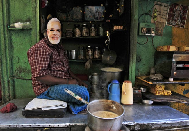  A tea stall vendor dons a PM Modi mask, highlighting the leader’s iconic chaiwala image across India.