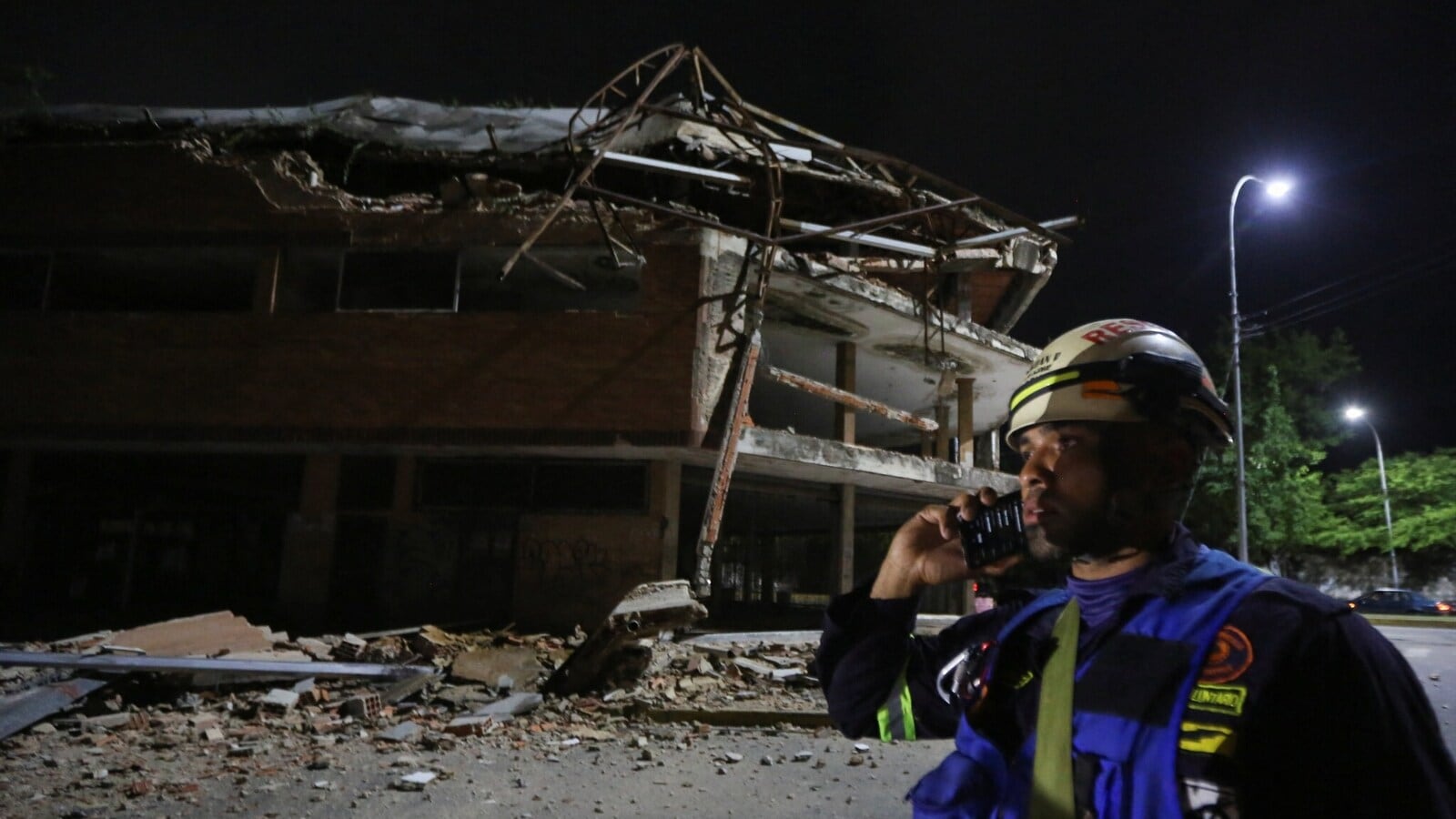 A firefighter stands next to a damaged building that used to house a university several years ago, after a strong earthquake, in Valencia, Venezuela, June 24, 2026. REUTERS/Juan Carlos Hernandez