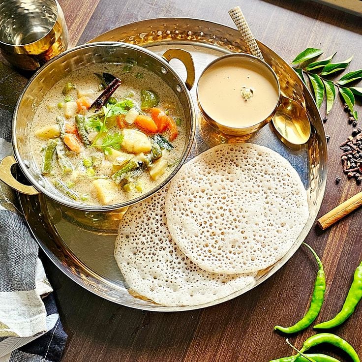 Appam And Stew – KeralaAppam, a soft-centred rice pancake with crisp edges, is a Kerala favourite. It is often paired with a mild vegetable or meat stew made with coconut milk, creating a comforting combination.