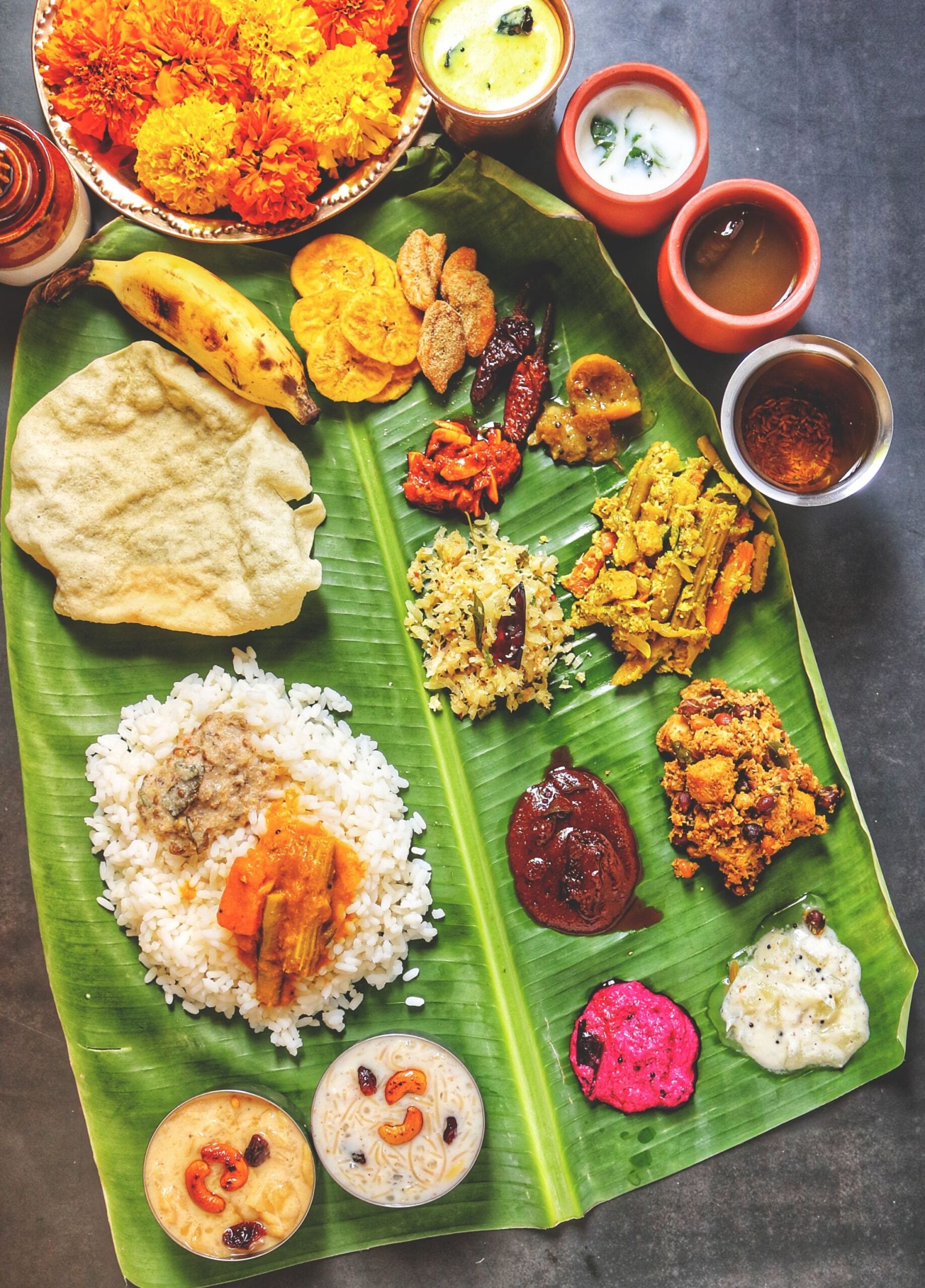 What Is Onam Sadya?One of the biggest highlights of Onam celebrations in Kerala is the Onam Sadya, or Onasadya—a lavish traditional vegetarian feast served on a fresh banana leaf. Often featuring more than 20 dishes, the elaborate meal brings together curries, vegetables, pickles, snacks, rice and desserts in a carefully planned spread. Preparing a Sadya is also a communal affair, with families spending hours cooking and assembling the feast.