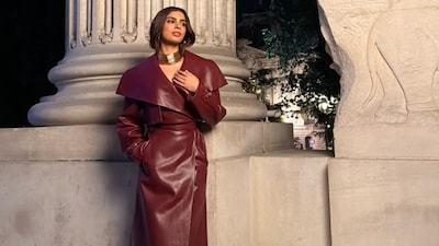 Khushi Kapoor gives Paris Fashion Week a burgundy twist in a glossy leather trench dress with a chunky gold choker from Messika for their show.