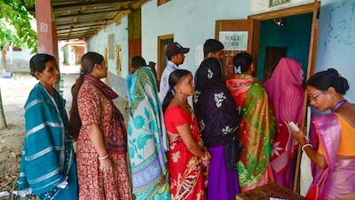 Voters stand in a queue to cast their votes for the Nagaon Lok Sabha by-poll, at a polling station in Buraburi, Morigaon district, Assam. (PTI photo)