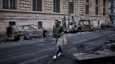 A man walks past a row of burnt out vehicles on Rue Yves Toudic destroyed after a nationwide protest against the "high cost of living", in central Paris on October 19, 2026. (AFP)