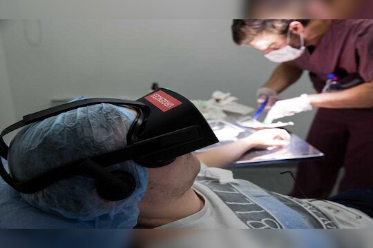 A nurse treats a patient wearing the 3D therapeutic virtual reality headset developped by Healthy Mind start-up, at the emergency service department of the Saint-Joseph Hospital in Paris, France, June 7, 2018. The headset immerses the patient in the heart of a Zen garden or an enchanted forest to counter the pain rather than increase the doses of painkillers. Picture taken June 7, 2018.   REUTERS/Philippe Wojazer - RC1AFB9B4880