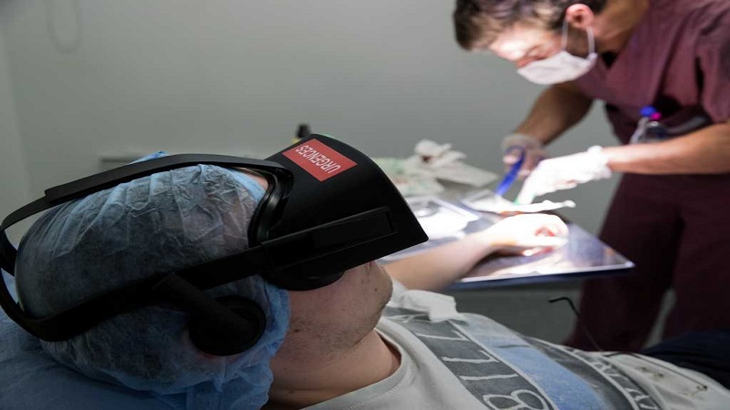 A nurse treats a patient wearing the 3D therapeutic virtual reality headset developped by Healthy Mind start-up, at the emergency service department of the Saint-Joseph Hospital in Paris, France, June 7, 2018. The headset immerses the patient in the heart of a Zen garden or an enchanted forest to counter the pain rather than increase the doses of painkillers. Picture taken June 7, 2018. REUTERS/Philippe Wojazer - RC1AFB9B4880