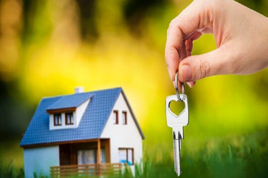 hand holding key against house background